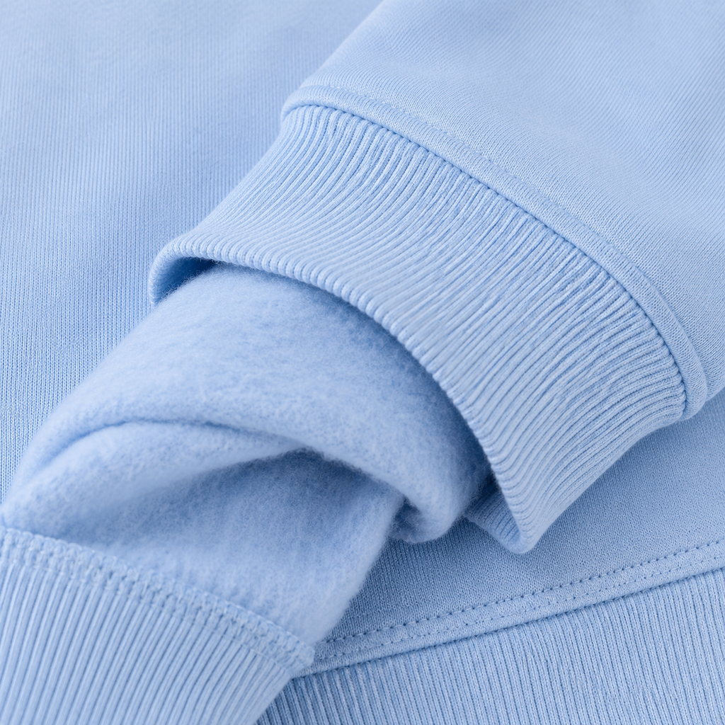 Zoom sur le poignet bord-côte et l'intérieur molleton gratté du sweat enfant bleu ciel