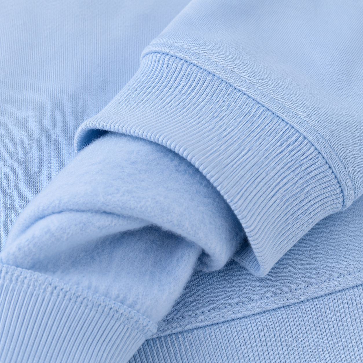 Zoom sur le poignet bord-côte et l'intérieur molleton gratté du sweat enfant bleu ciel